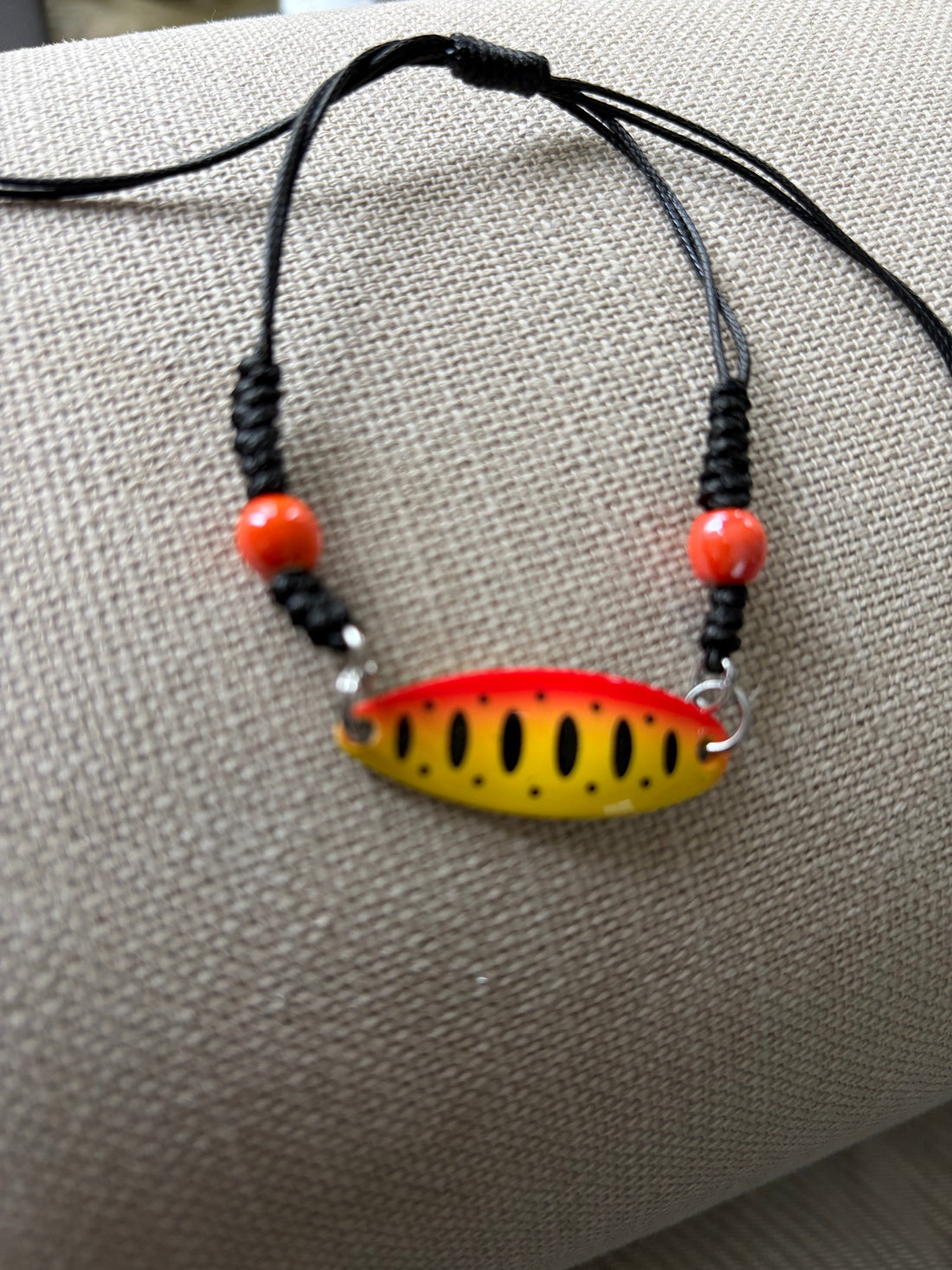 Lure Bracelet with yellow and red centerpiece, featuring black and orange beads, perfect for aquatic adventure accessories.
